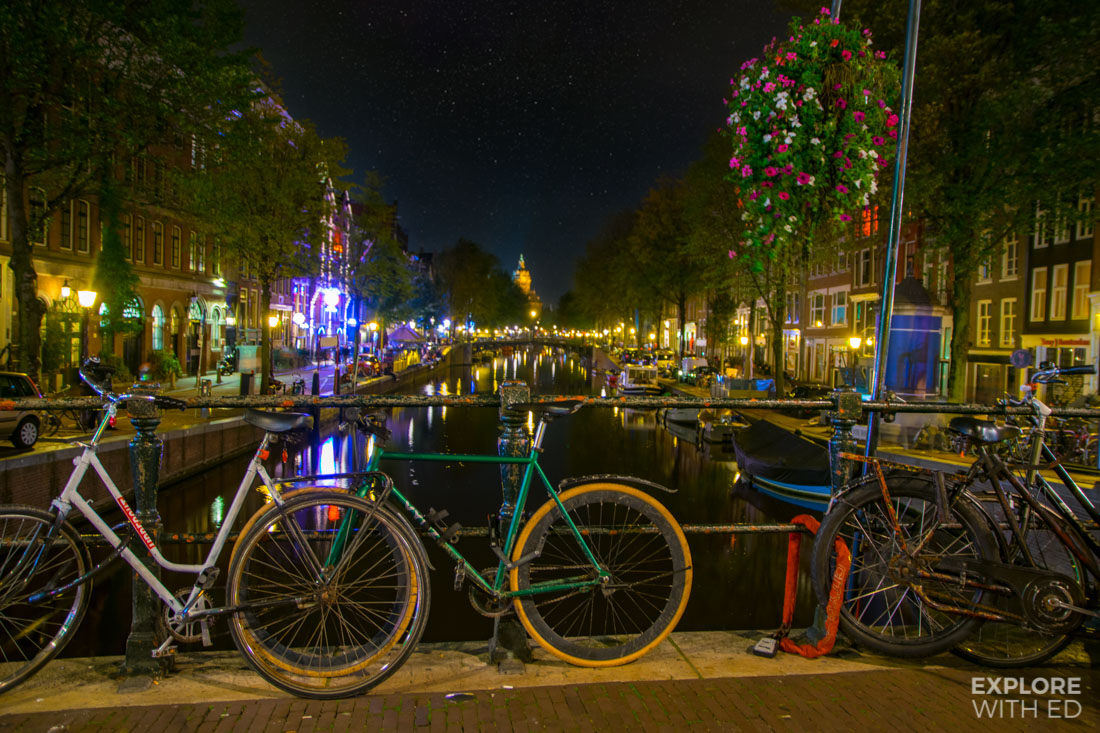 Bicycles lining Amsterdam's canal bridges at night looking towards Centraal