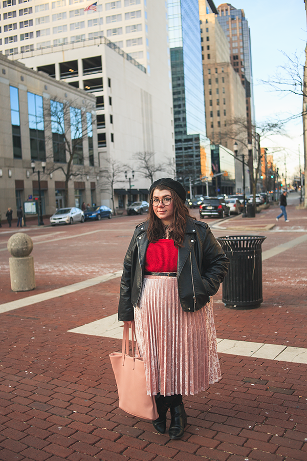 An outfit of black beret, black faux leather moto jacket, peter pan collared berry paisley dress, red sweater, pink velvet midi skirt, black tights with red hearts ala polka dots, black heeled chelsea boots and pink tote bag.