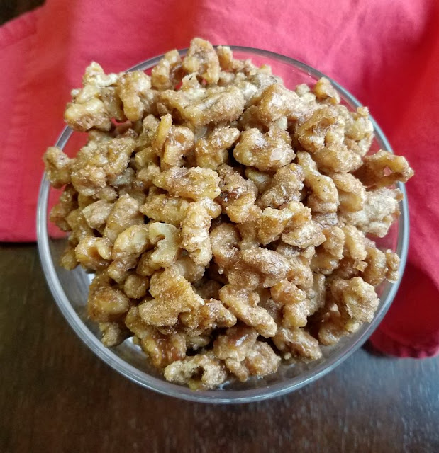 Super simple candied walnuts are spiced with the taste of fall, cinnamon, nutmeg and a hint of cloves. They are great on salads, as a garnish or eaten as is! bowl full of candied walnuts with cinnamon and spices on them