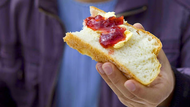 Man eating a bread slice of Strawberry jam and yoghurt curd