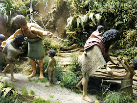 Diorama of a 19th-century Maori family being guided along a track in the bush by a pakeha man.