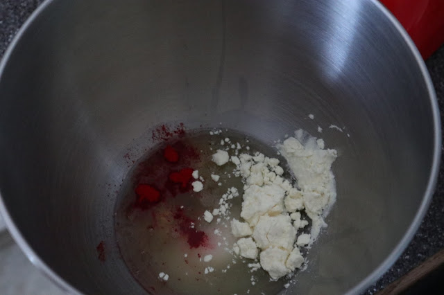 Red power colour, albumen, granulated sugar and egg white in the bowl of a stand mixer.
