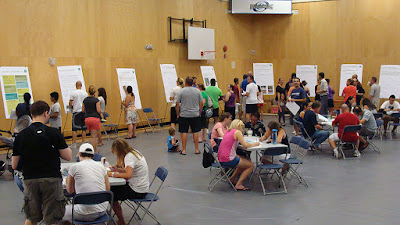 open house, many people sitting at tables and at flip charts