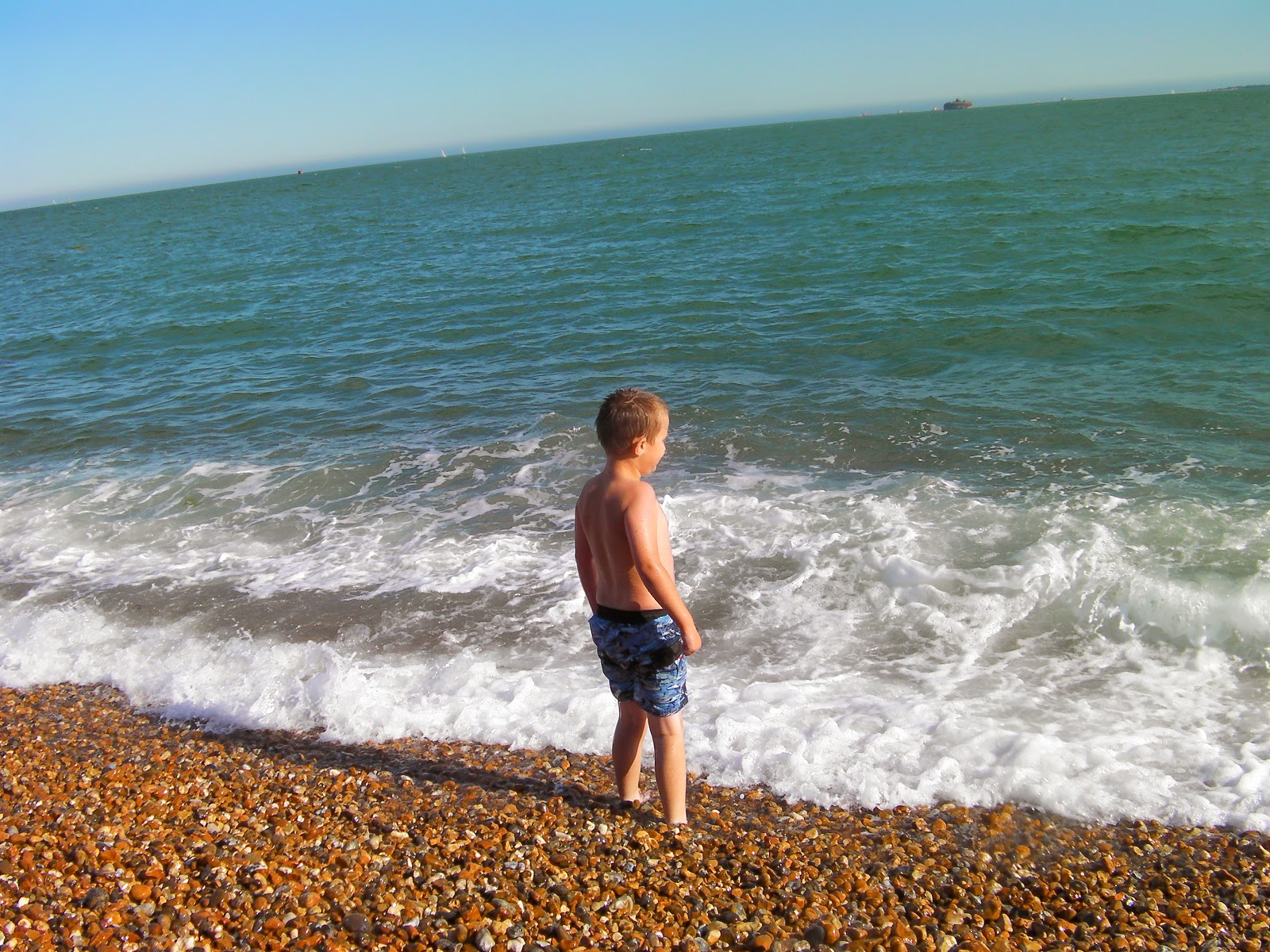 boy swimmer standing on shingle seashore by pyramids centre like a man who stands in front of the sea