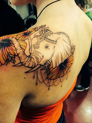 Um elefante com um cocar é adornado com um cocar, miçangas e flores.