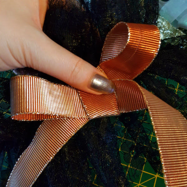 Deciding on a trim, bronze metallic ribbon bronze metallic ribbon tied into a bow held against black lace