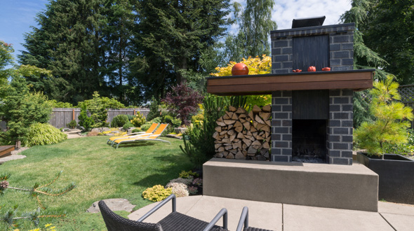 Backyard landscape with trees surrounding a fireplace