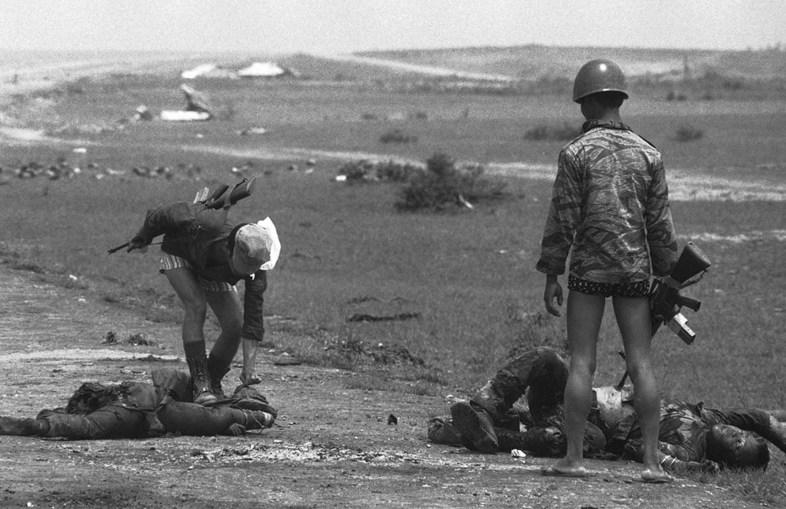 South Vietnamese Marines check the bodies of dead soldiers for cigarettes near My Chanh, new government defense line 20 miles north of Hue, on May 5, 1972. The soldiers were killed during fighting when Quang Tri City was abandoned.