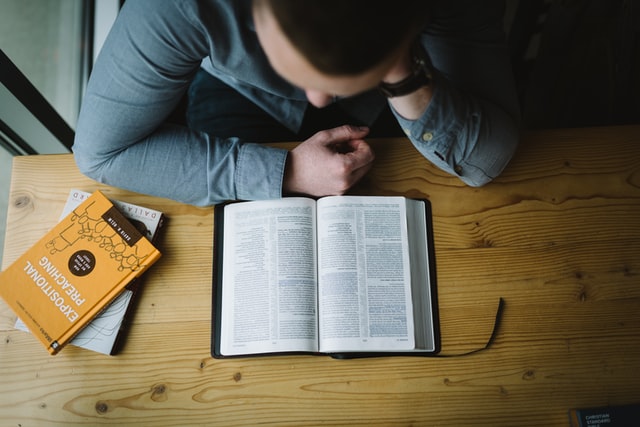To Reject False Doctrines, Fortify Your Mind with the Word of God A man seated on a table studying the Bible