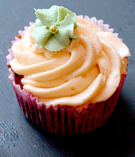 Sweet potato cupakes with an orange buttercream icing decorated with a green paste flower