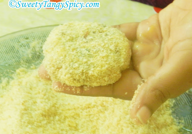 Rolling the coated tapioca cutlets in breadcrumbs.