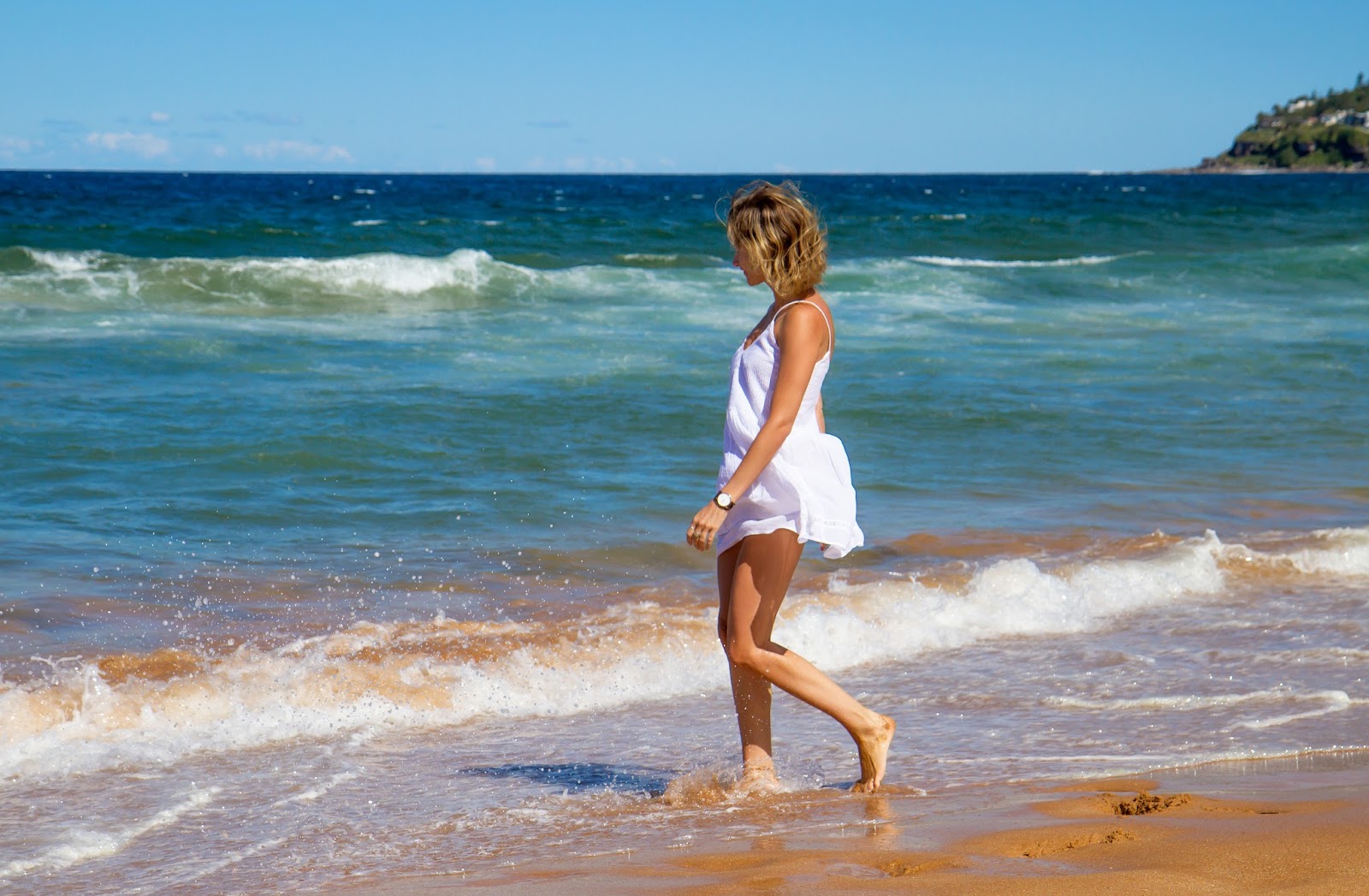 fashion and travel blogger, alison hutchinson from Styling My Life is playing in the waves at Palm Beach in Sydney, Aystralia in a white Zara sundress.