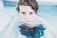 Image of boy child in the pool listening learning to blow bubbles