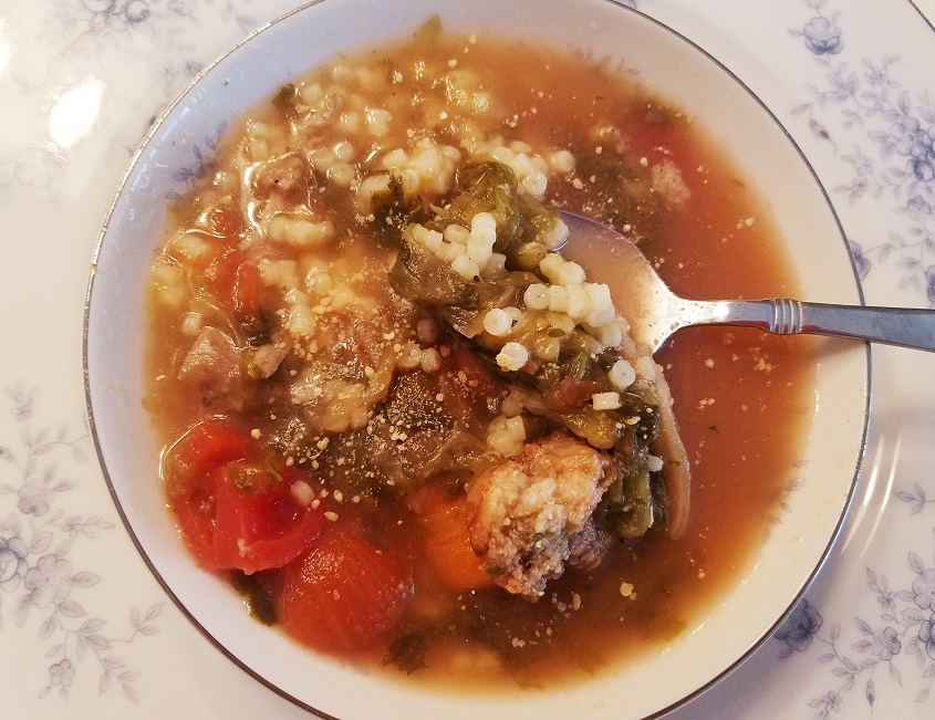 This is a bowl of wedding soup with little pastine in it and escarole, carrots in a chicken broth.