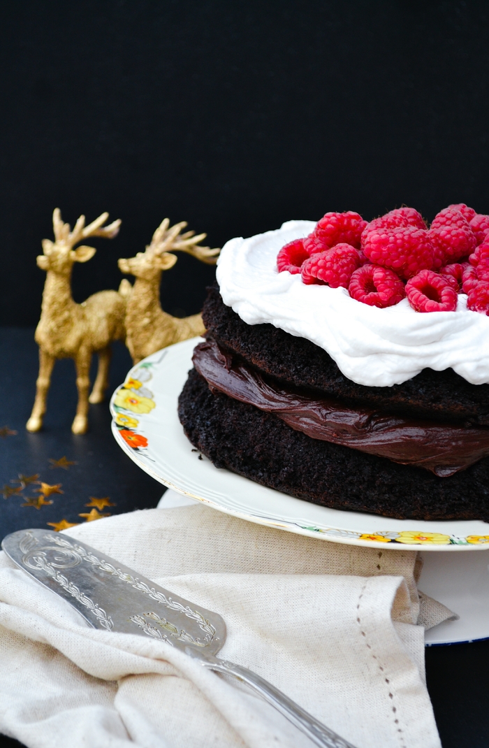 An indulgent chocolate cake filled with chocolate buttercream and topped with whipped coconut cream and raspberries. Suitable for vegetarians and vegans.
