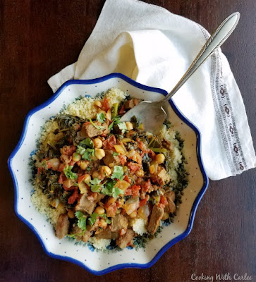 Moroccan Lamb Stew is hearty, flavorful and warm. It is perfect nestled on a bed of couscous and is sure to leave you full and satisfied. serving spoon in bowl of lamb stew and couscous