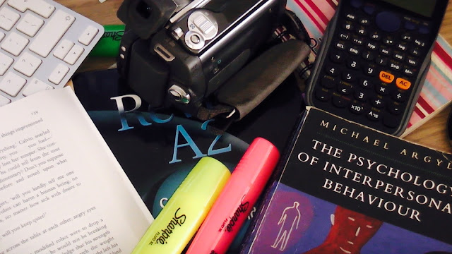 a pile consisting of a cam corder, calculator marker pens, key board and books