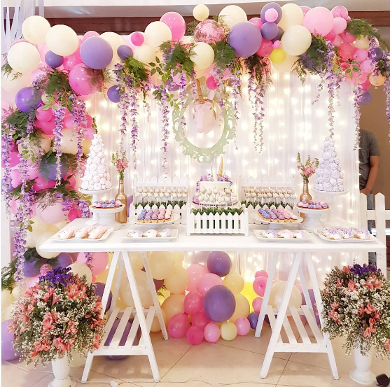 La mesa de dulces se resalta con la guirnalda de globos y flores en