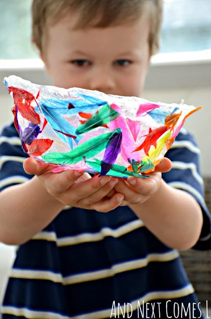 A child holding a DIY feather bowl craft idea for kids