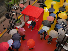people with umbrellas waiting in line to take photos at an Adidas promotion