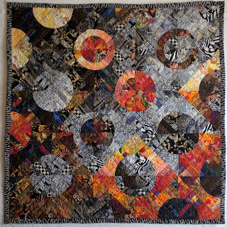 Drunkard's Path quilt variation uses fabric of one-inch strings to add depth. Black, white, grey, brown, and orange.