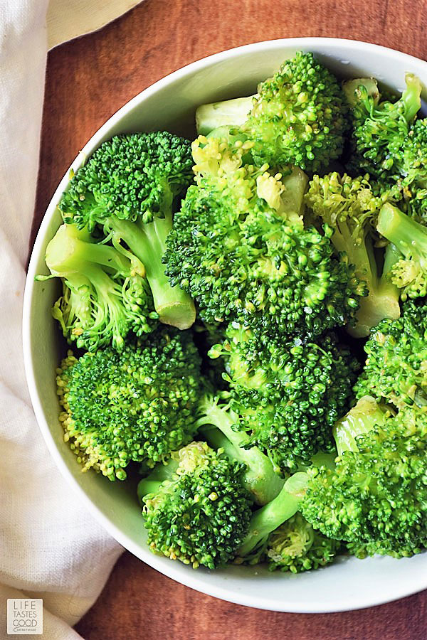 Overhead view of fresh broccoli in a white bowl. Learn how to steam broccoli to perfection