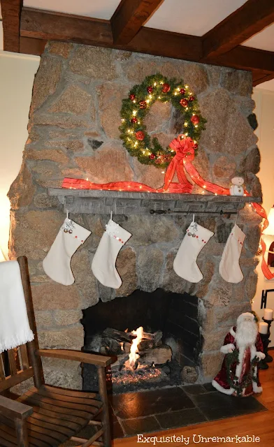 Lighted wreath and stockings on stone fireplace