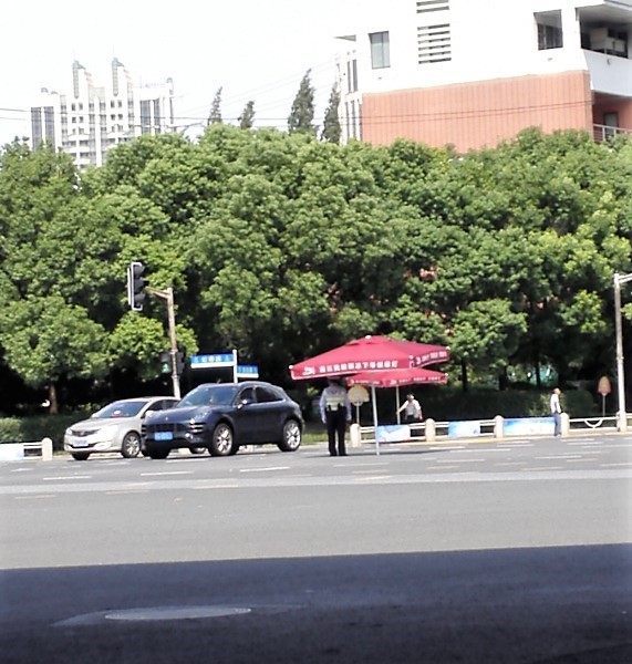 上海の古北地区にある巨大な交差点で交通整理をする警官がパラソルの下にいる