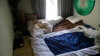 Bedding in accommodations. Futons sitting on the tatami mat floor.