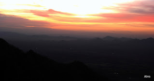 "A scenic view of Mount Abu: A breathtaking view of Mount Abu, with the rising sun in the forground and lighting up golden glow on the mountains and the surrounding landscape."