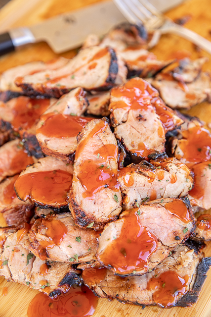 Orange Chipotle Grilled Pork Tenderloin - only 4 ingredients including the pork! So simple and packed FULL of amazing flavor! Pork tenderloin marinated in orange juice, BBQ sauce and chipotle chili powder. Drizzle cooked pork with more BBQ sauce. Great for lunch, dinner and cookouts. SO easy and delicious! #pork #grill #grilling #grilledpork #porktenderloin cooked pork tenderloin slices drizzled with BBQ sauce
