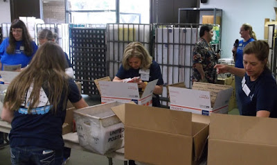 Volunteers busy packing boxes filled with Girl Scout cookies.