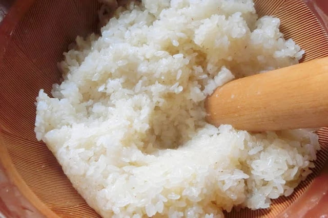 蒸された餅米を綿棒で押しつぶす。