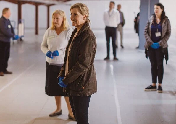 The Countess of Wessex visited the warehouse facility of the Woking Foodbank at Sheerwater. brown coat and pink sweater