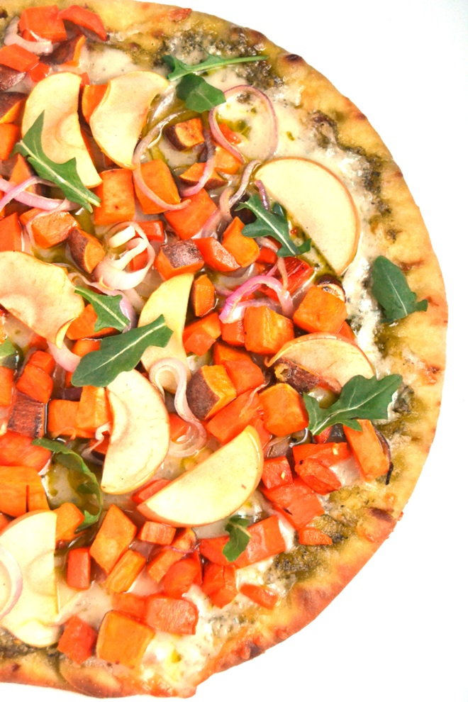 White Cheddar and Pesto Roasted Vegetable Pizza is a flavor loaded, easy pizza with roasted sweet potatoes, carrots, apples and red onions and is topped with fresh arugula for a peppery bite. www.nutritionistreviews.com