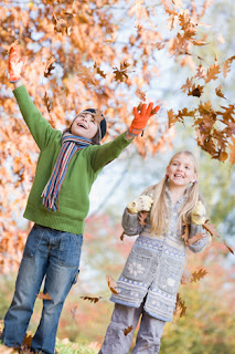 Photo of two children playing in the autumn leaves