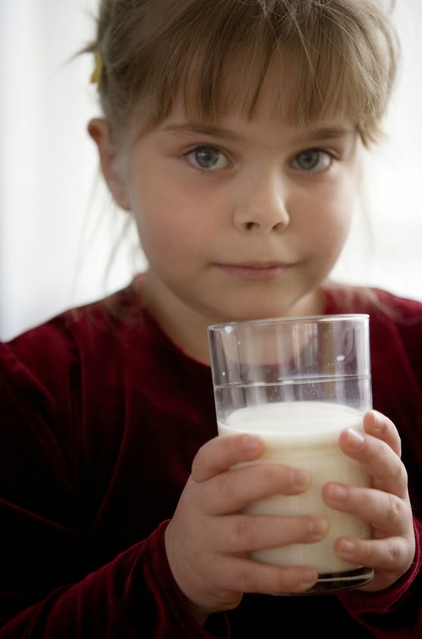 Lovely kid drinks a glass of milk