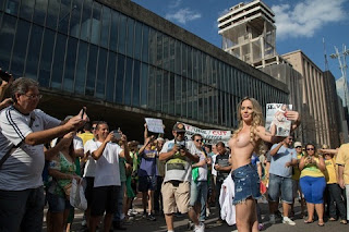 Ju Isen faz toplees mais uma vez em manifestação Ju Isen repetiu o feito no início do ano e tirou a roupa novamente durantes as manifestações que aconteceram neste domingo, 16. A socialite chegou na Avenida Paulista, em São Paulo, vestindo uma camiseta branca que já evidenciava a ausência de sutiã.
