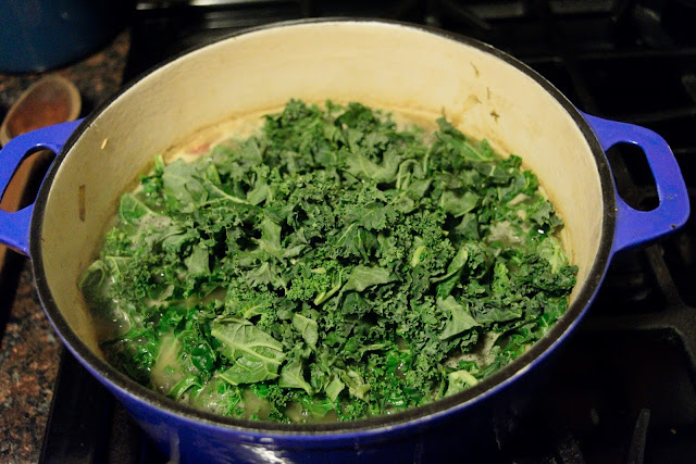 The kale being added to the soup. 