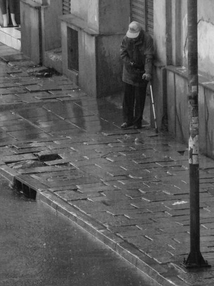 homem de muleta na chuva