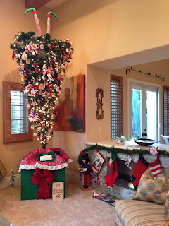 Upside-down elf tree An upside-down Christmas tree on a red, pink and green stand with elf legs sticking out of the top