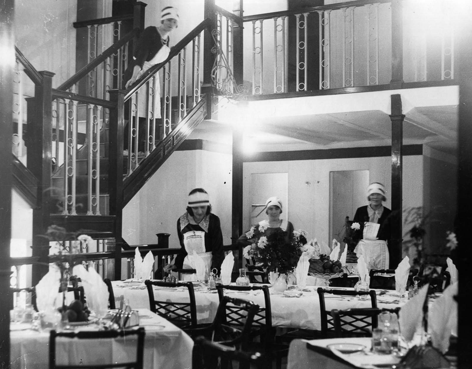 Maids set up tables in the lounge for a meal. 1929.