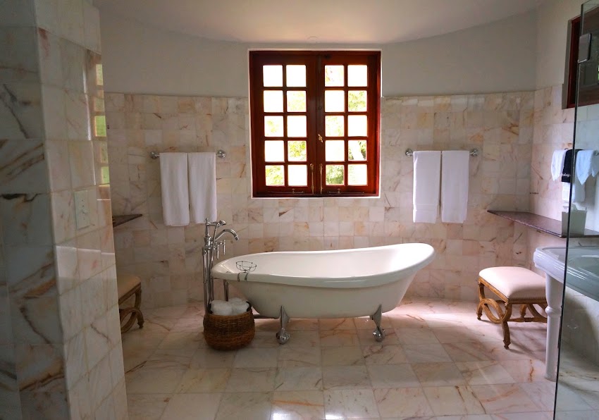 White Bathtub on White Tile Bathroom Near Brown Framed Clear Glass Window White Bathtub on White Tile Bathroom Near Brown Framed Clear Glass Window