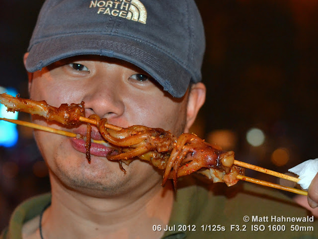 China, Beijing, Donghuamen night market, Chinese food delicacies, unusual food, bizarre Chinese foods, exotic food, portrait, Chinese man eating bizarre food, Chinese man eating fried squids