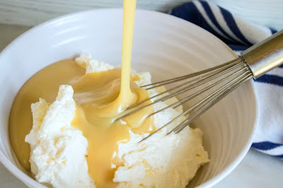 pouring sweetened condensed milk over whipped cream