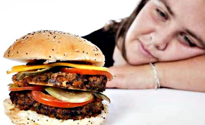 Mujer con sueño mirando una hamburguesa Las ganas de dormir que se presentan luego de comer se pueden evitar