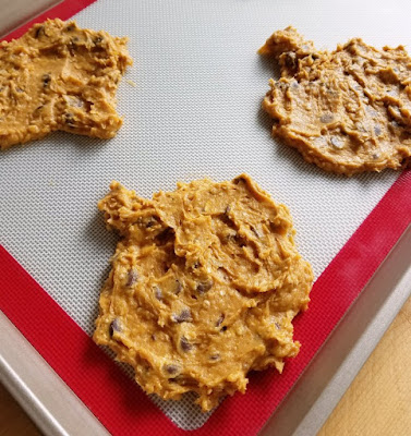 cookie dough shaped into pumpkins on baking sheet ready to bake