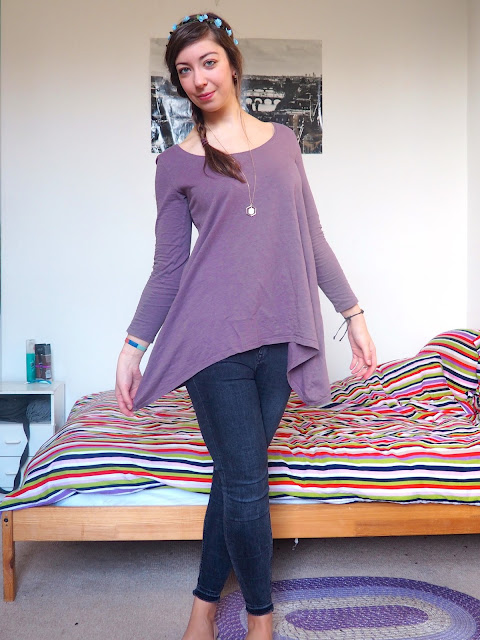 Rapunzel Disneybound outfit of long lavender tunic top, grey skinny jeans, nude ballet flats, and blue flower crown