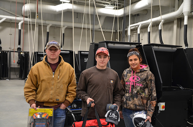 Three students stand in welding lab and are holding gear