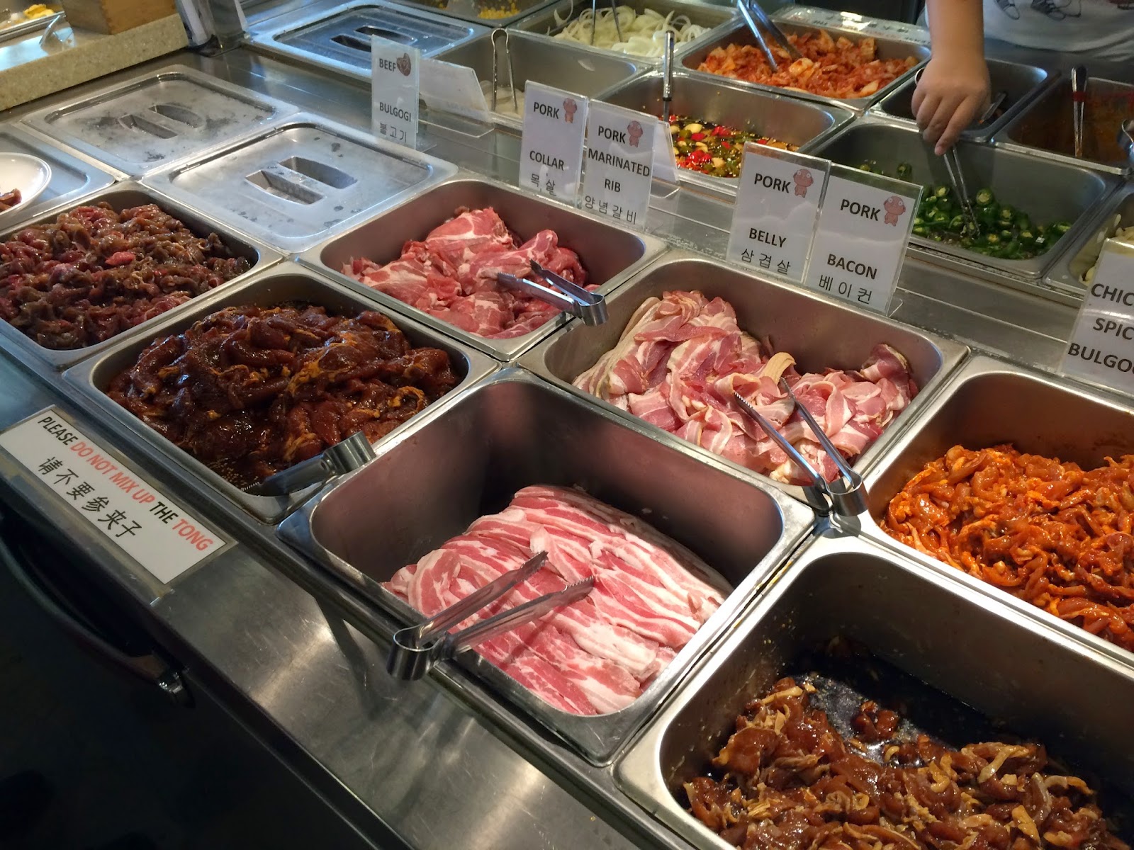 Korean BBQ buffet with meats, vegetables, and sauces.